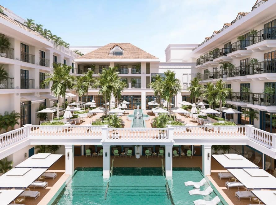 Elegant courtyard-style hotel with two levels of pools, surrounded by palm trees, sun loungers, and white balconies, blending classic architecture with a tropical resort atmosphere.
