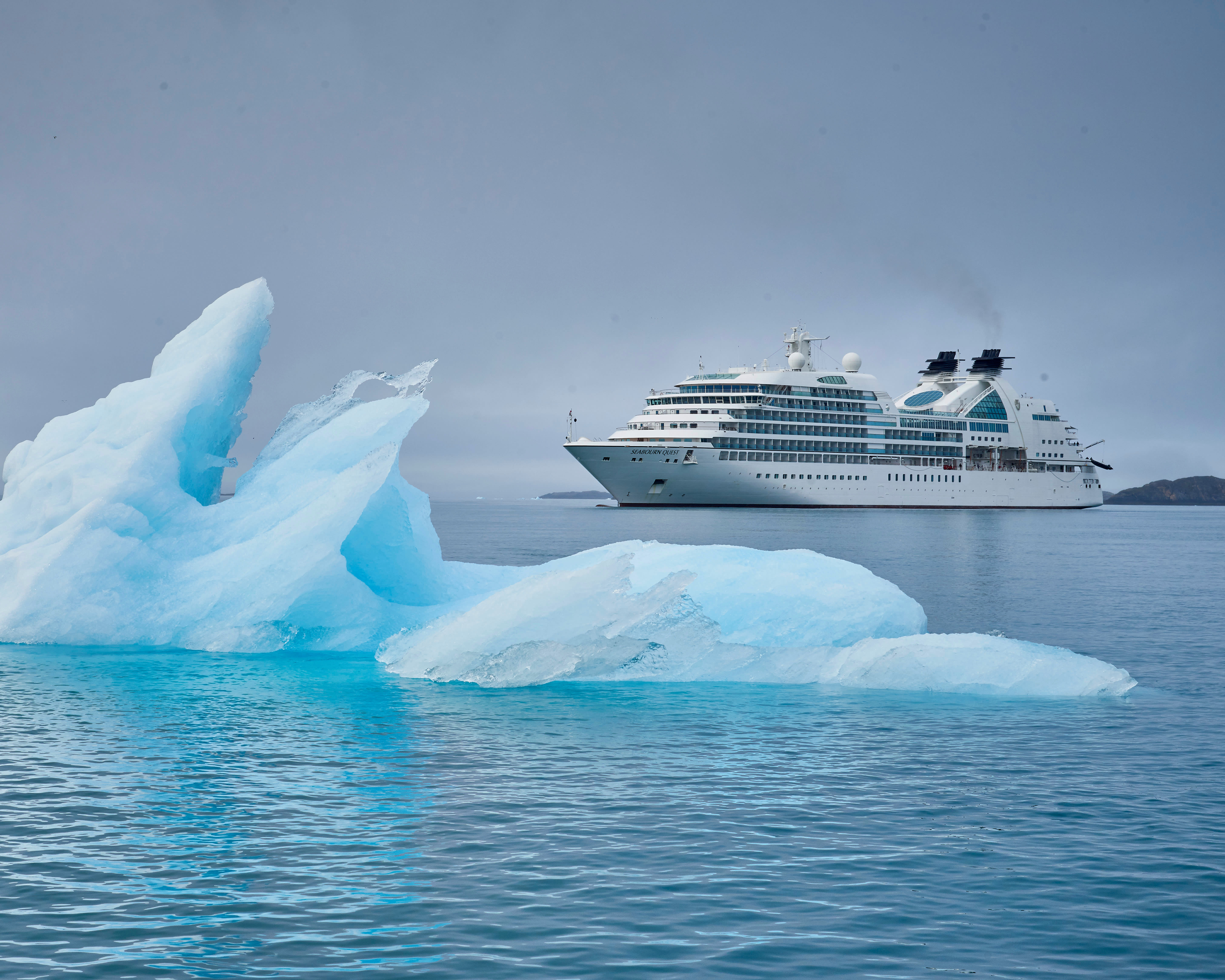 boutique white cruise ship under grey skies sailing in icy waters