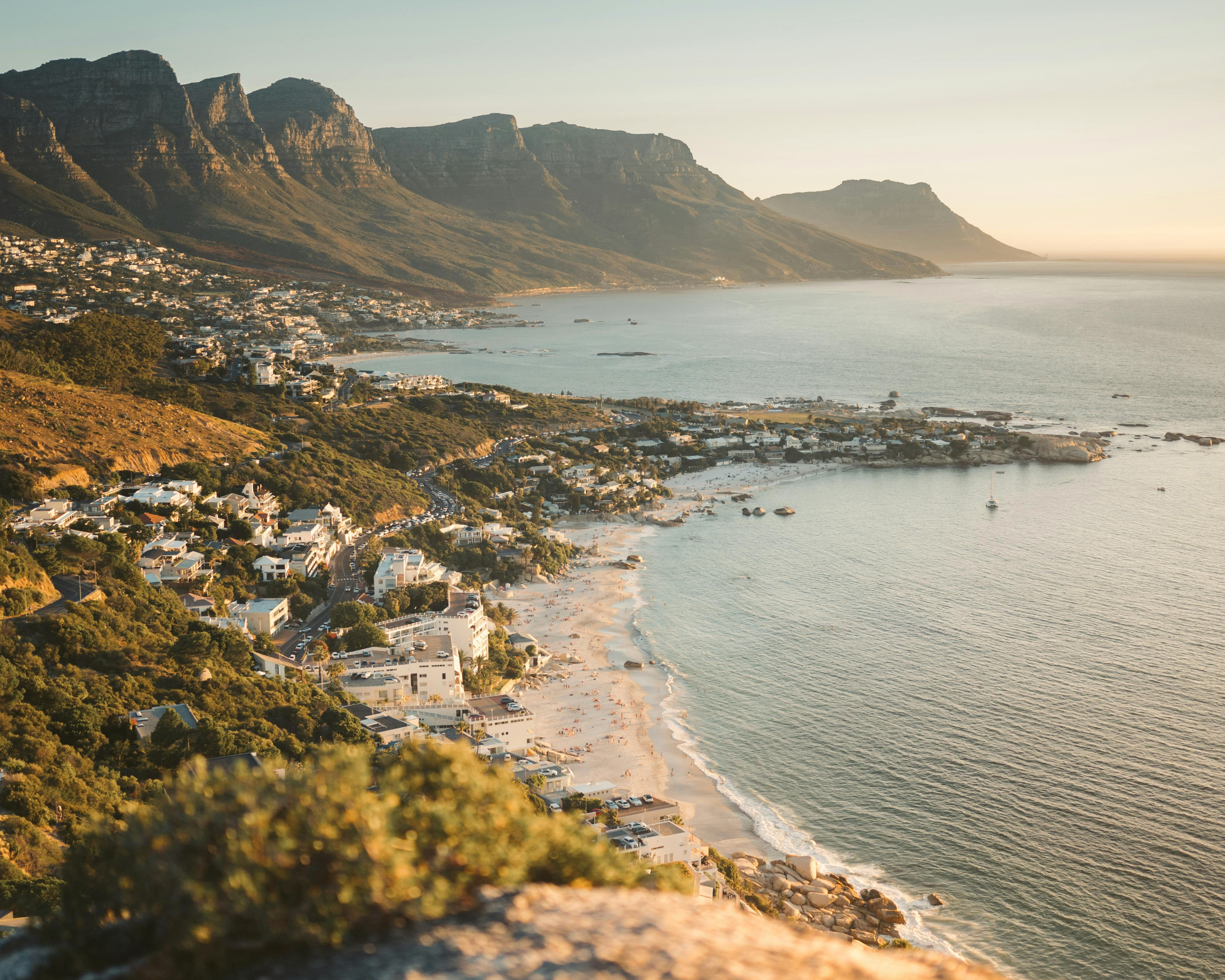 aerial view of coastline with hillside homes and tall mountains during day