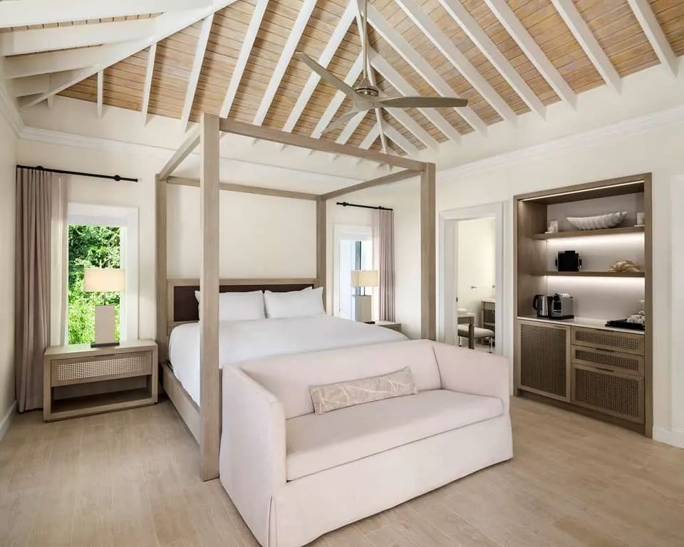 white vaulted wood beam ceiling, gray four poster bed, with white sofa at the foot of the bed.