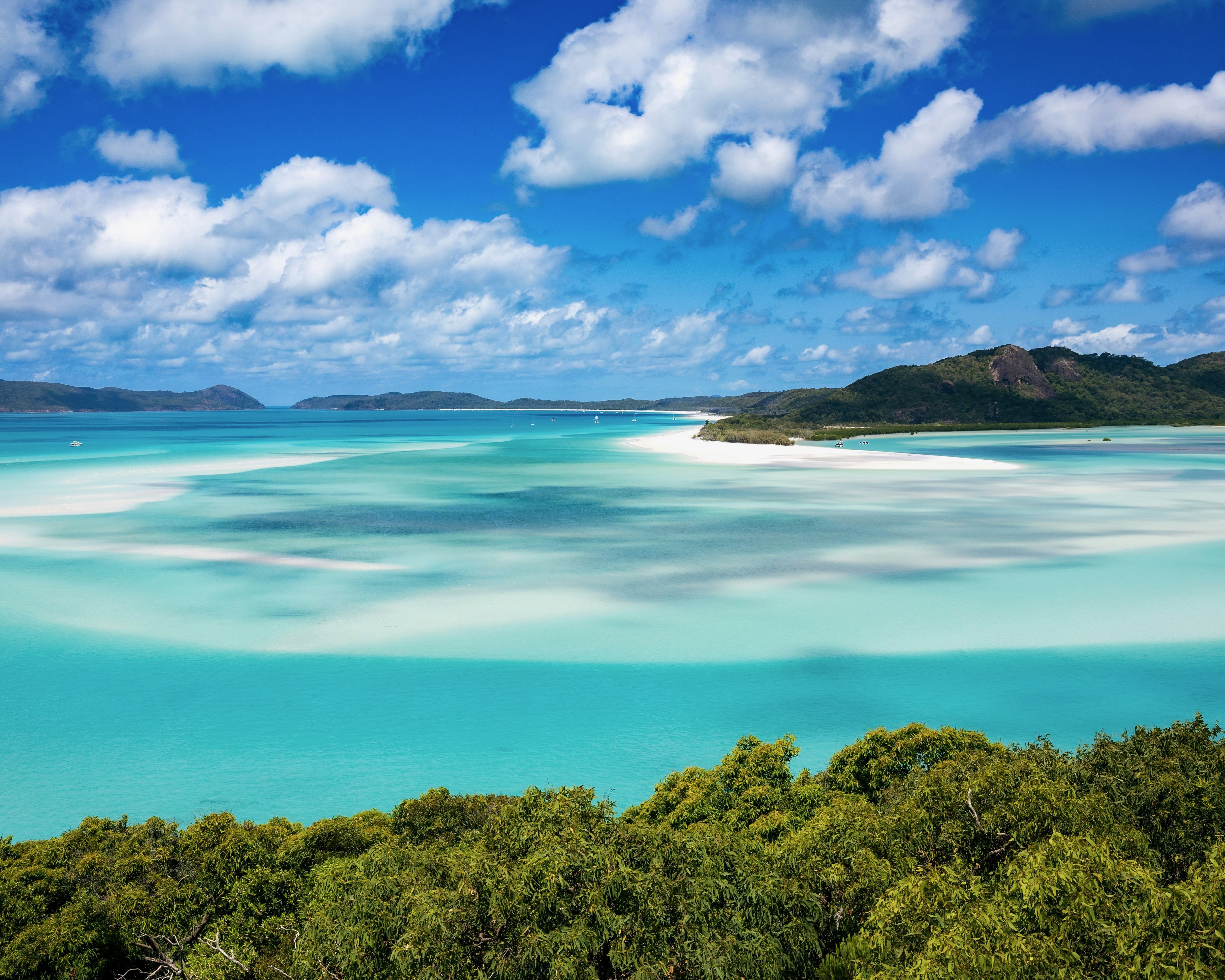 green mountains above turquoise waters with white sandbanks swirled throughout during day