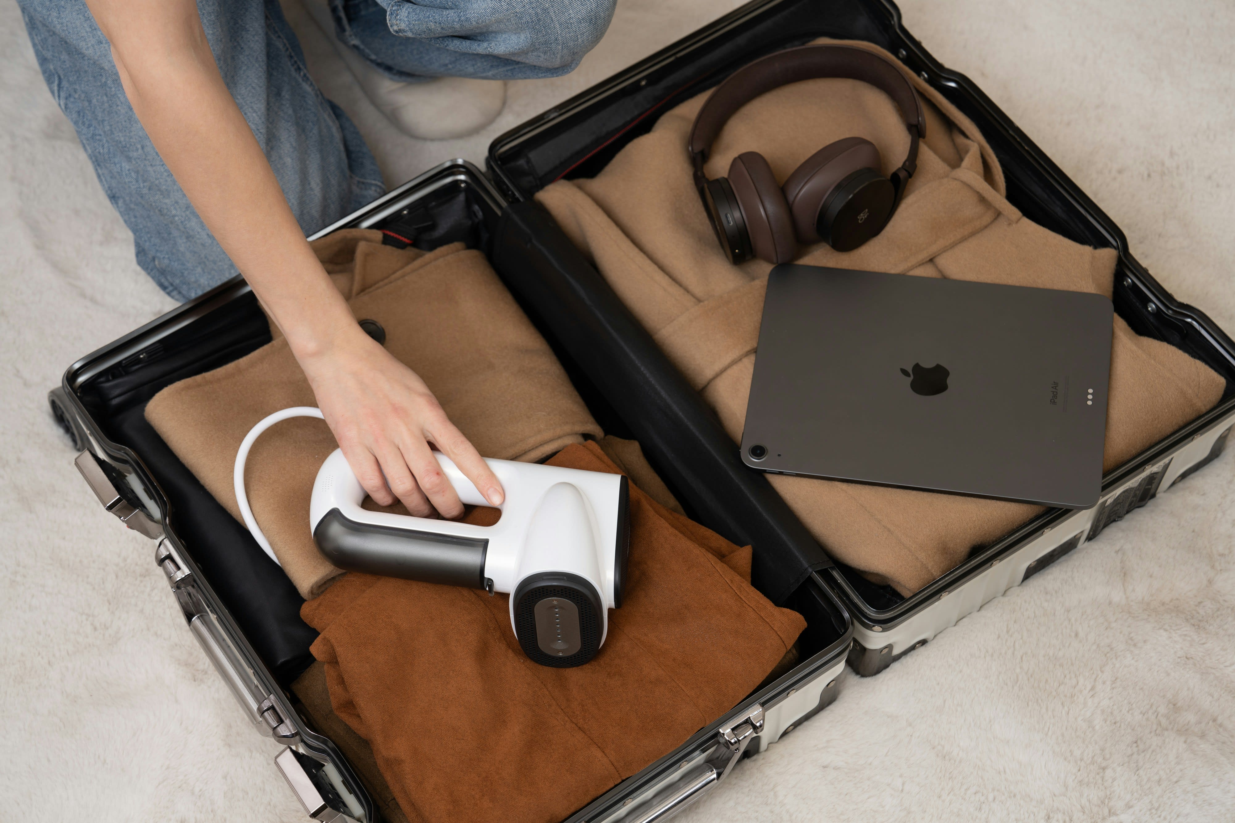 open suitcase with brown clothing and a computer
