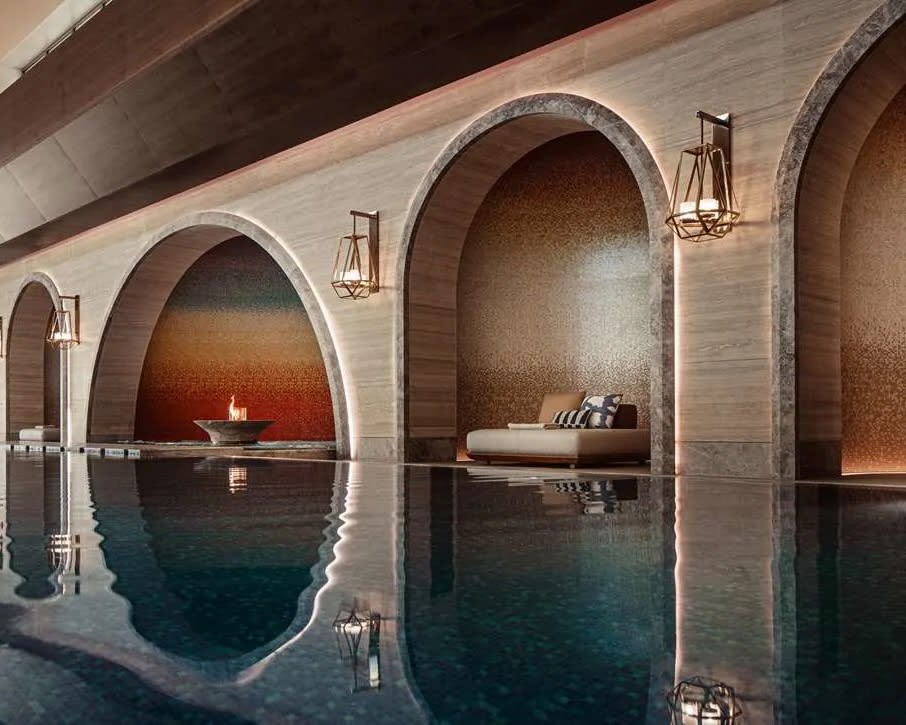 A spa pool next to a lounger in a tan stone arch