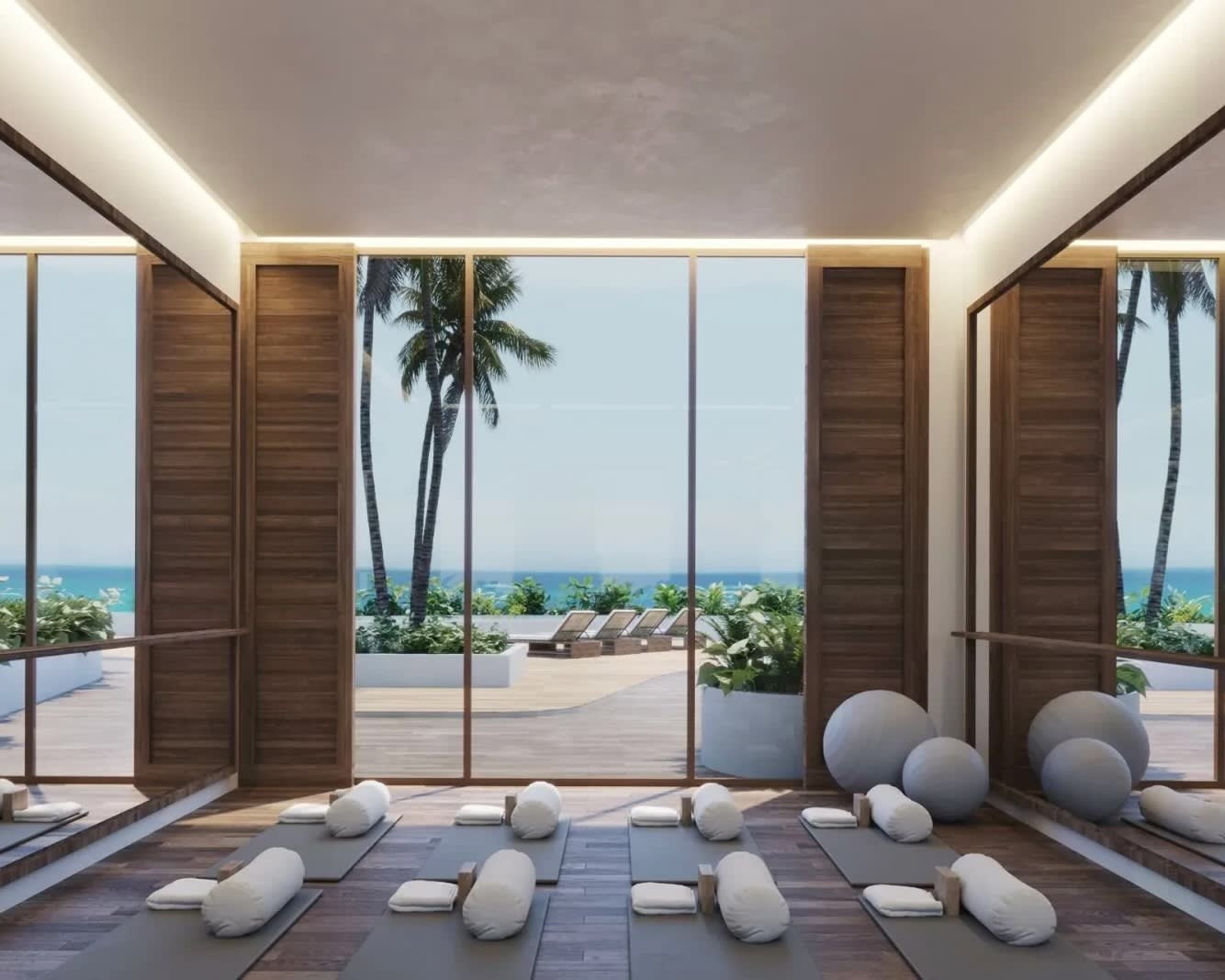 private yoga studio with mats overlooking a pool and beach during day outside floor-to-ceiling glass windows