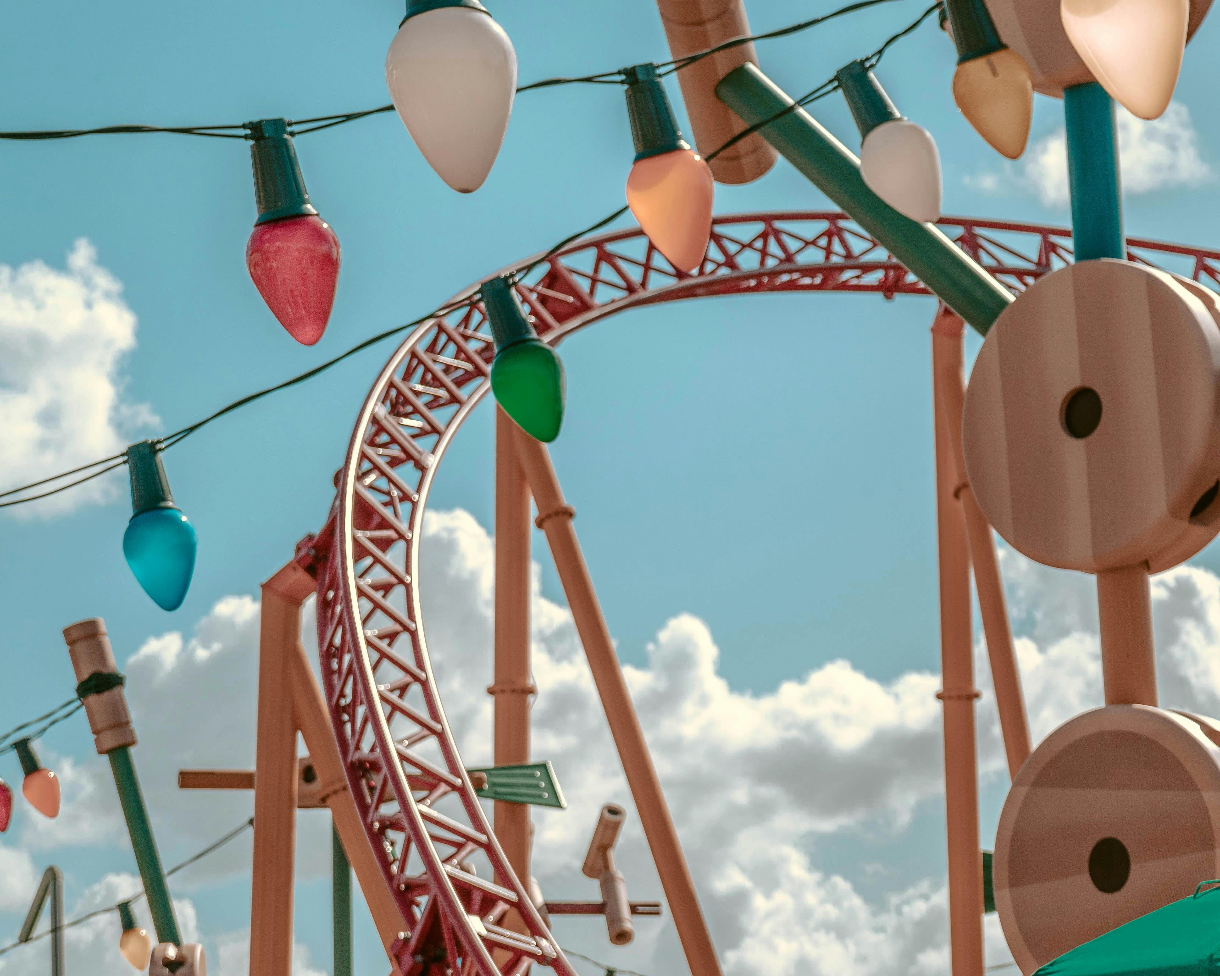 red roller coaster track in the background during day with christmas lights in the foreground
