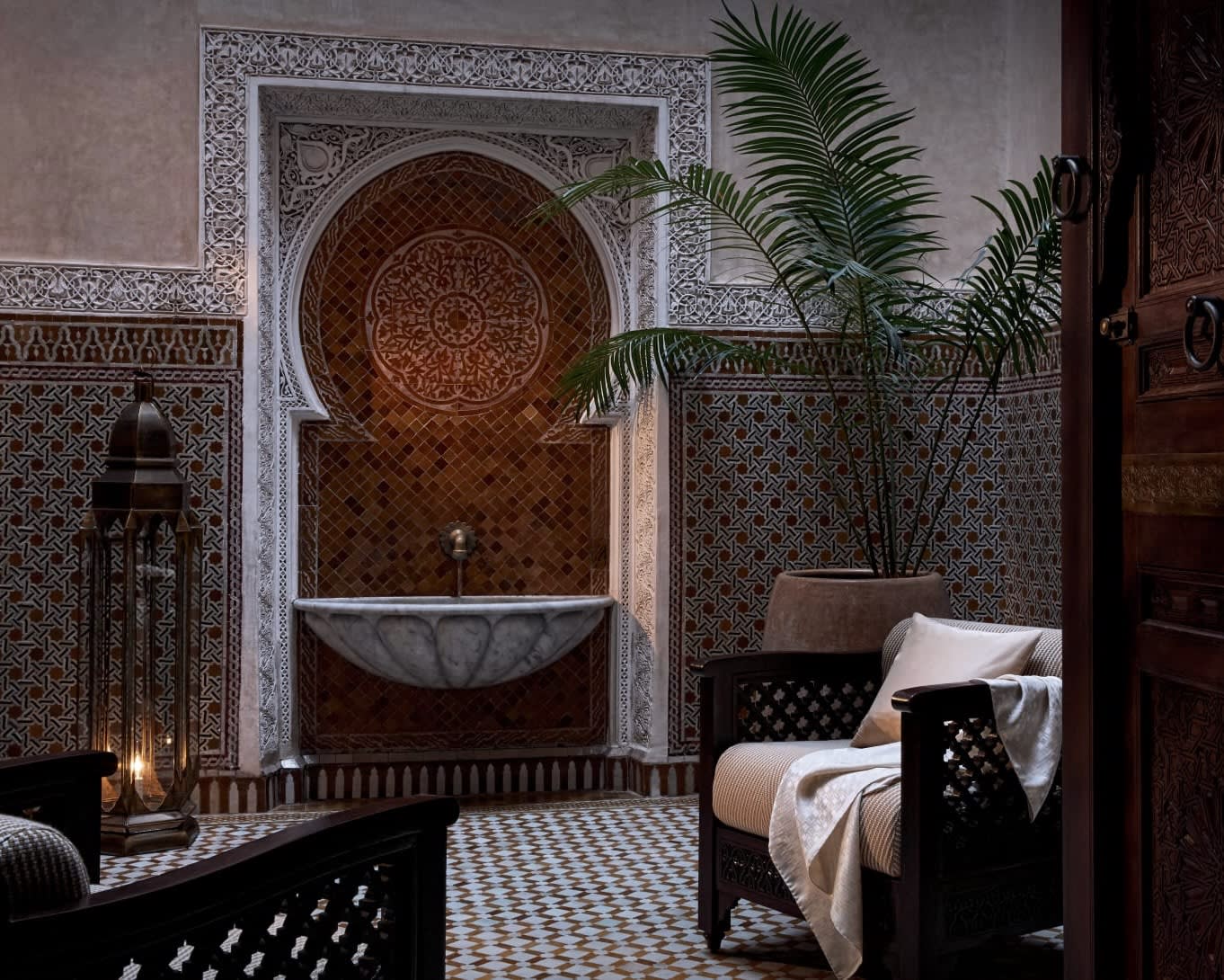 room with decorative tile floors and wall with fountain, with chairs and a potted plant