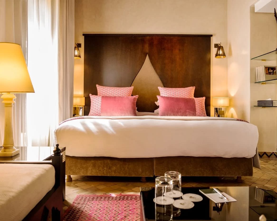 hotel room with wood bed frame, white linens, and decorative pillows