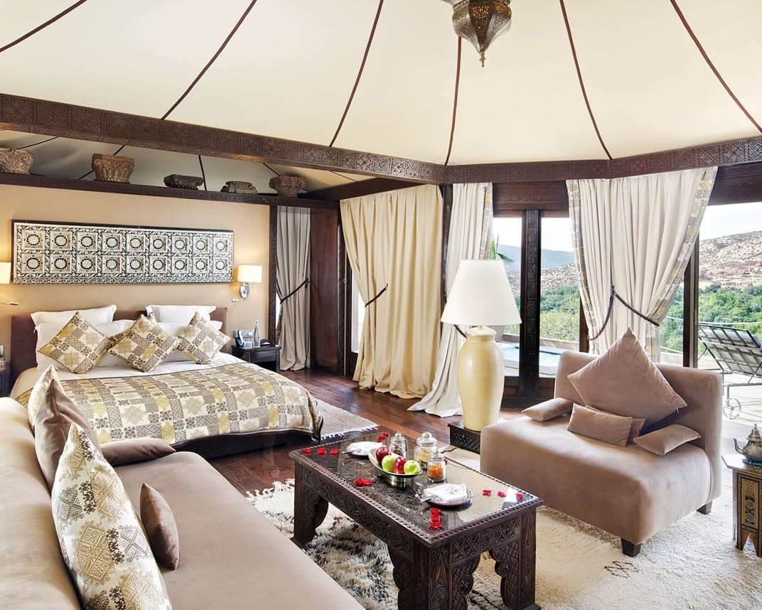 tented hotel room with dark brown accents, cream walls & ceiling, with tan furniture