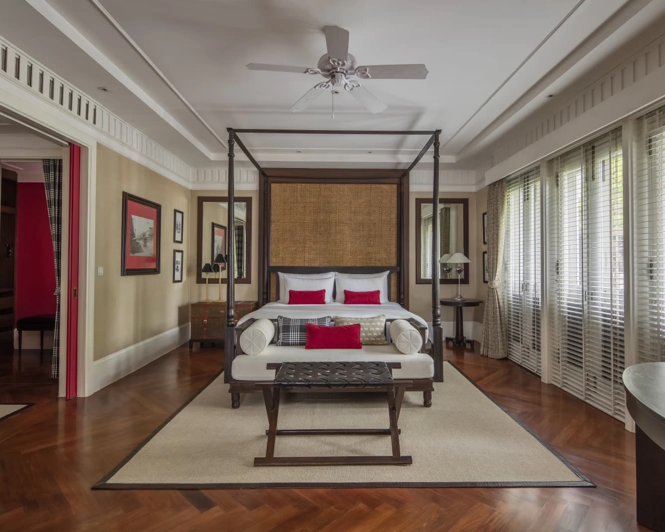 four poster black bed with red accents, wood floors, and white linens