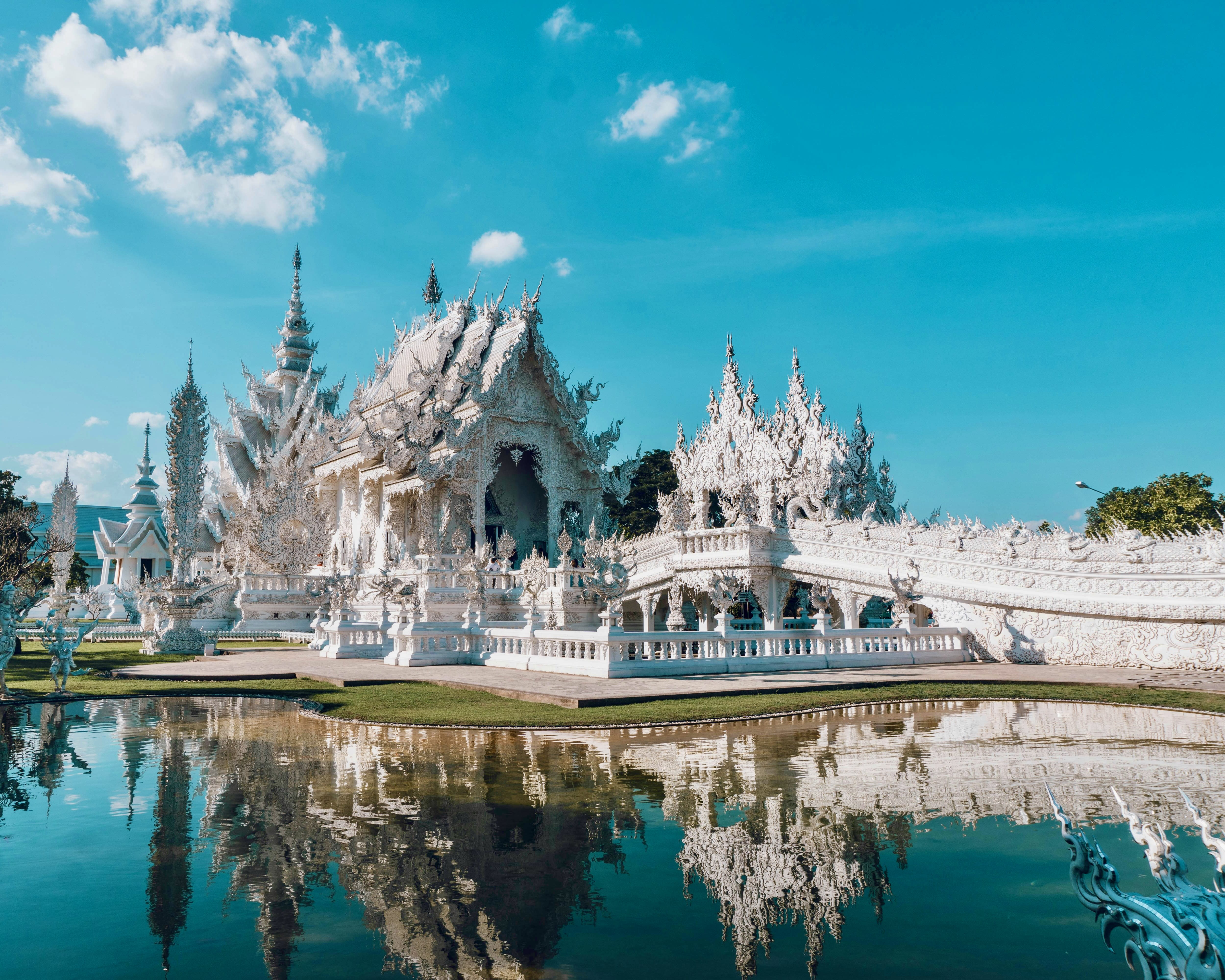 intricate modern white temple with reflecting pool and blue skies