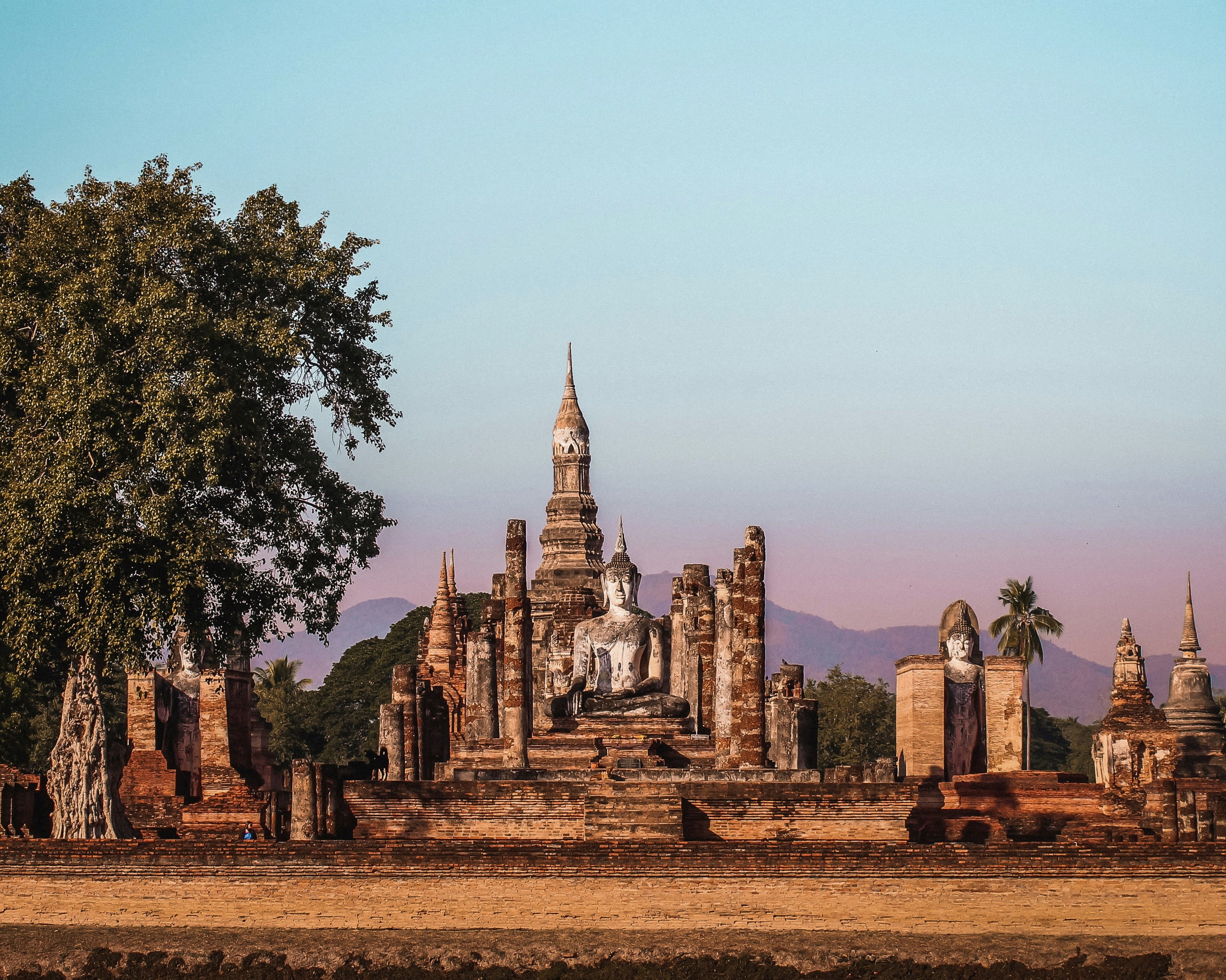 an ancient temple complex with buddha statue at dusk with trees