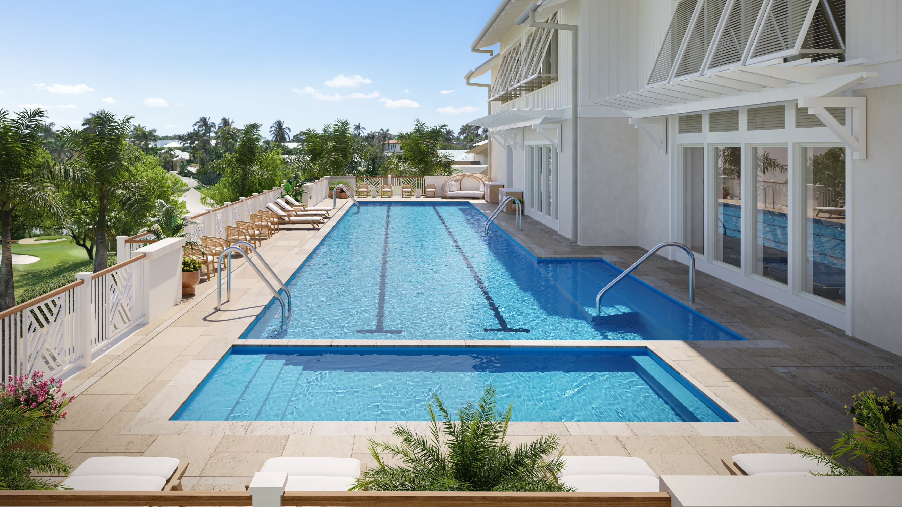 Sunlit rooftop lap pool at a luxury spa, with clear blue water, swim lanes, and steps, surrounded by white loungers, wicker chairs, palm trees, and a breezy coastal-style building overlooking tropical greenery.