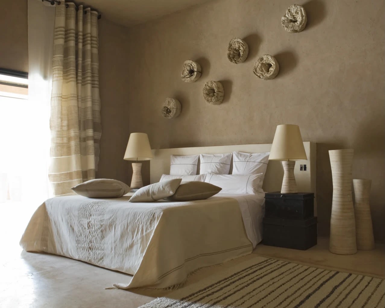 earth tone rustic room with bed, nightstands with lamps, and wall artwork of a hotel room