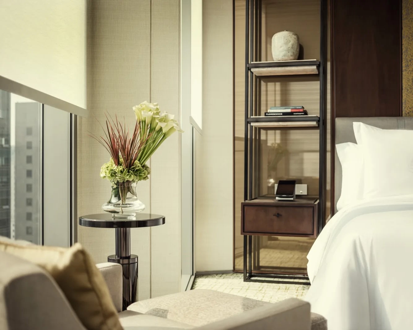 flower arrangement in glass vase on side table next to a window in a bedroom
