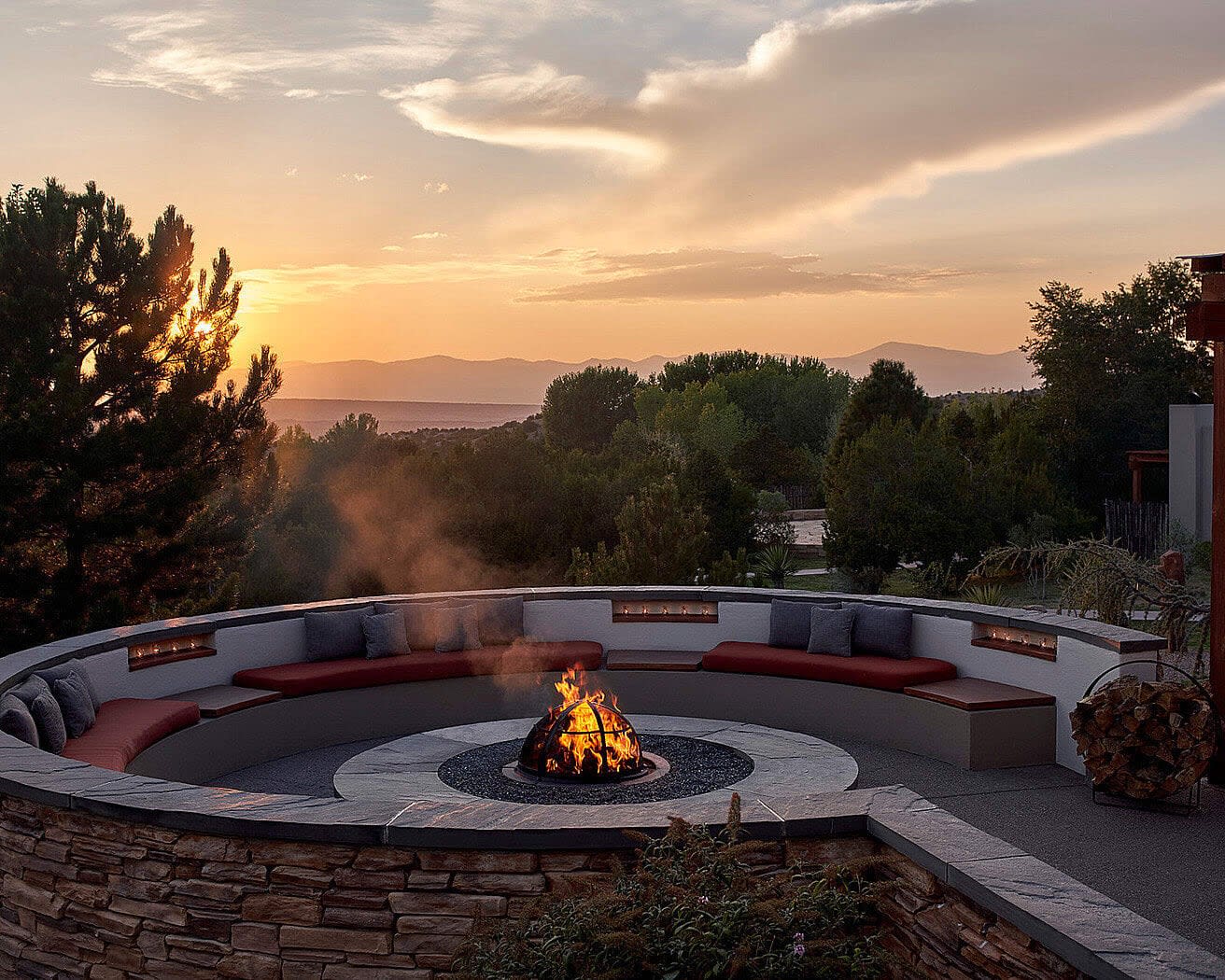 circular firepit with seating in front of trees and the sun setting