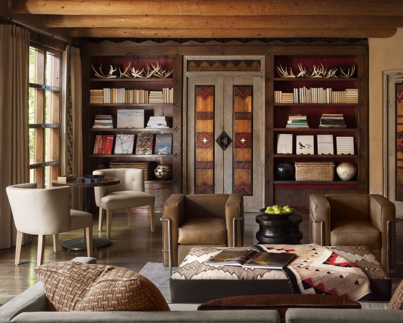 library living room with brown leather chairs, a table with two chairs, and shelves filled with books