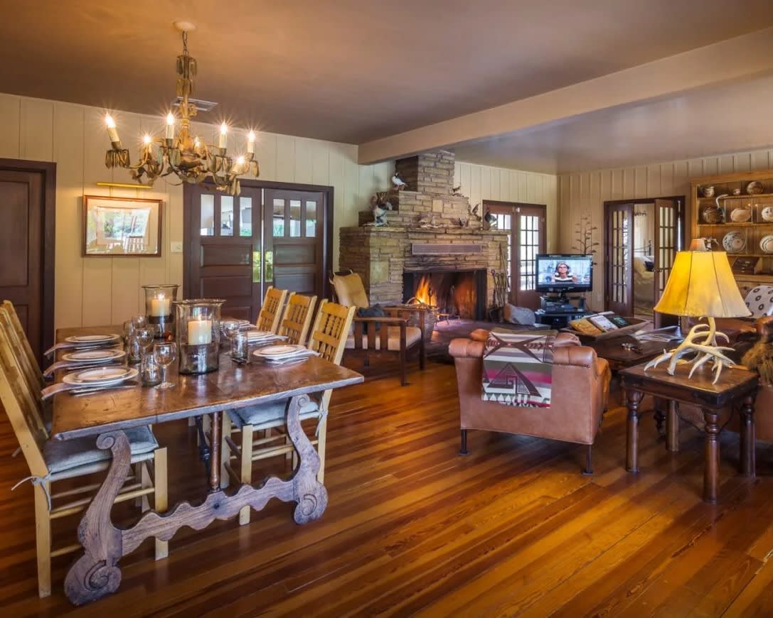 living and dining room with wood furniture, chandelier over table, and stone fireplace