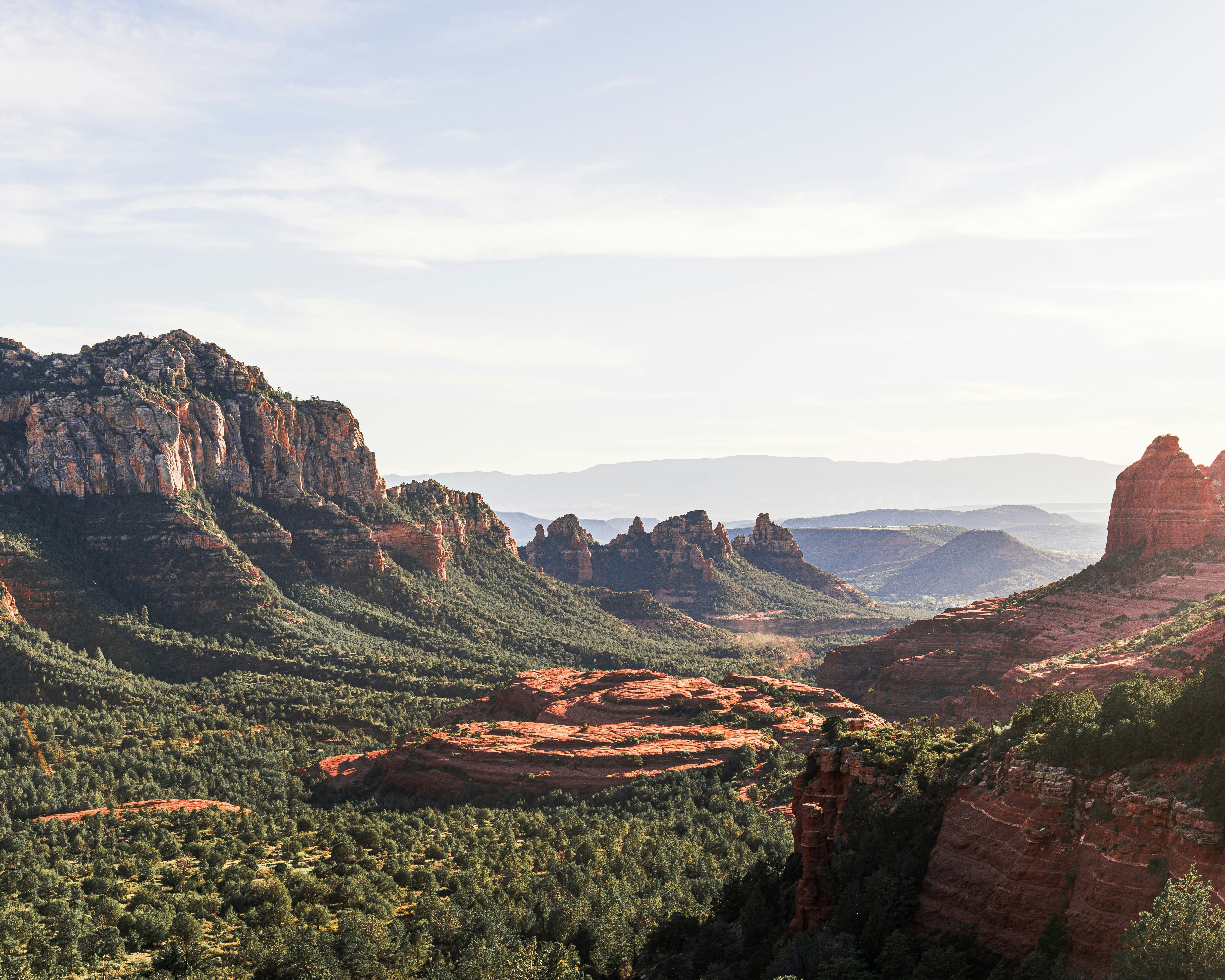green valley with red rocks and steep mountain cliffs during day