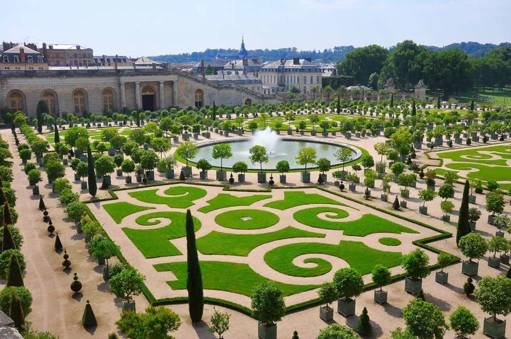 View of the gardens at Versailles featuring manicured paths and the exterior of Le Grand Controle