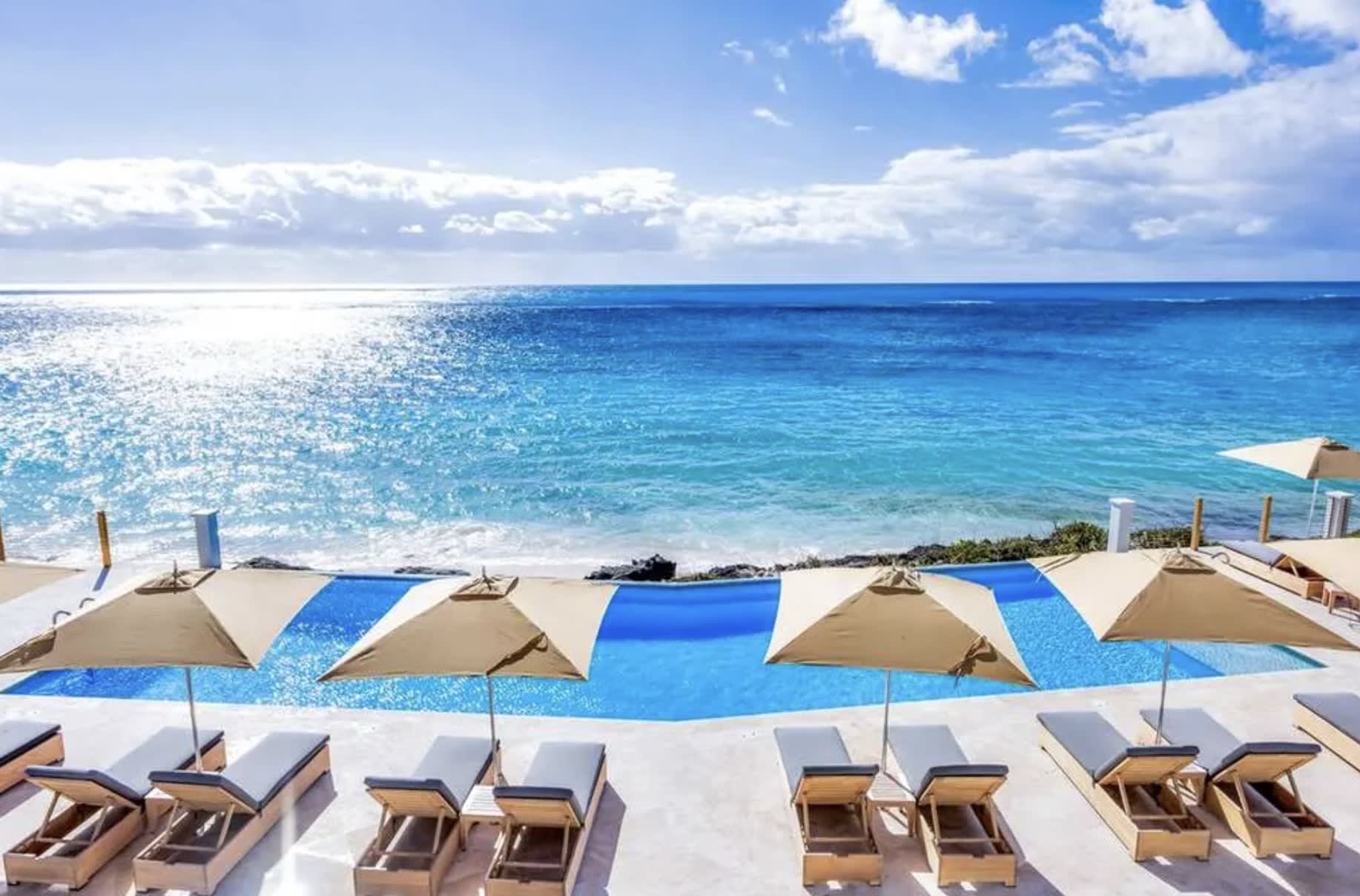 infinity pool with umbrella and blue ocean