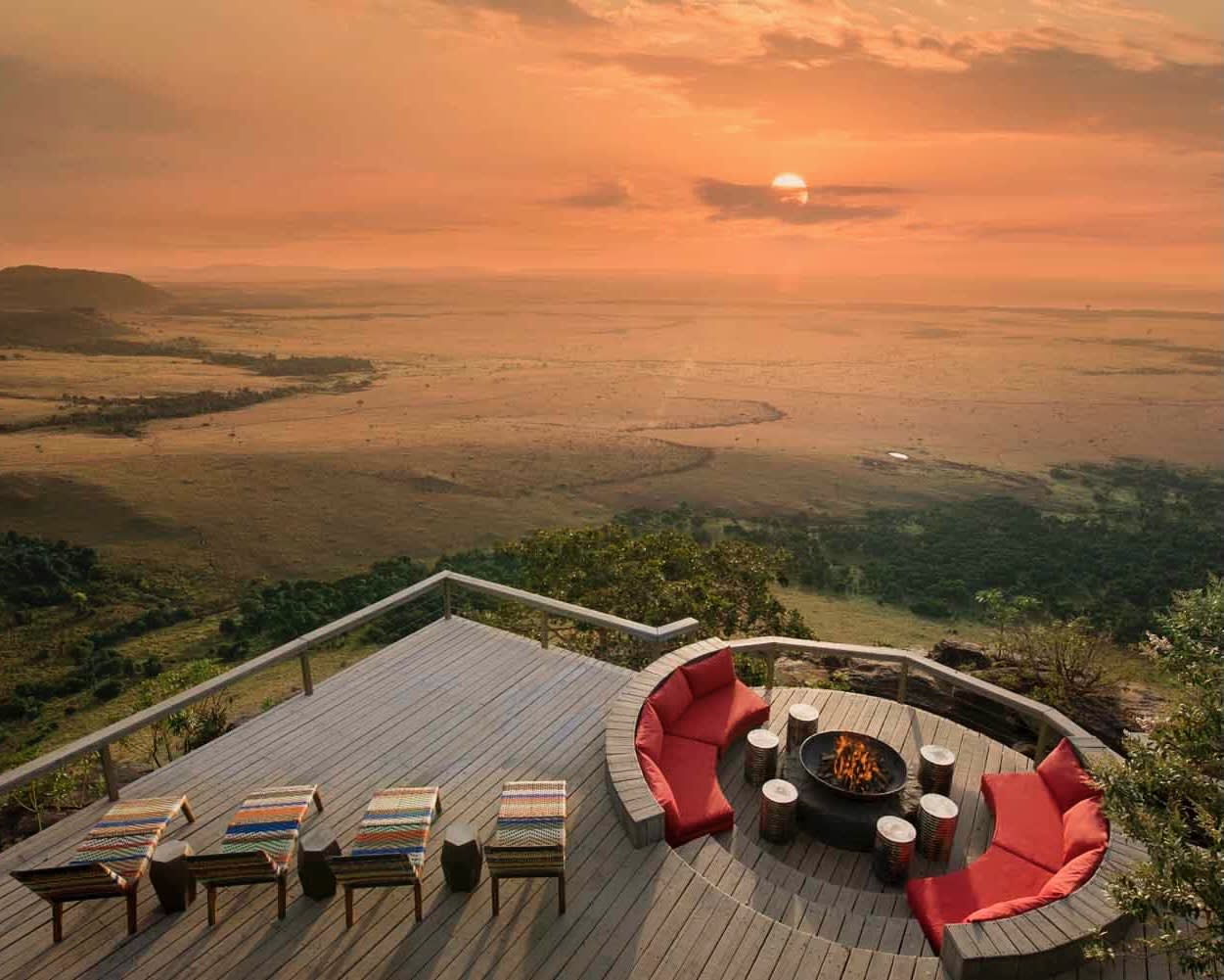 deck with lounge chairs overlooking a vast savannah plain with the sun setting on the horizon