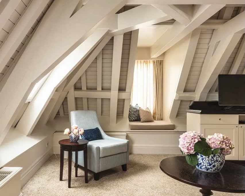 white wood beam sloped ceiling over a chair and wood furniture during day