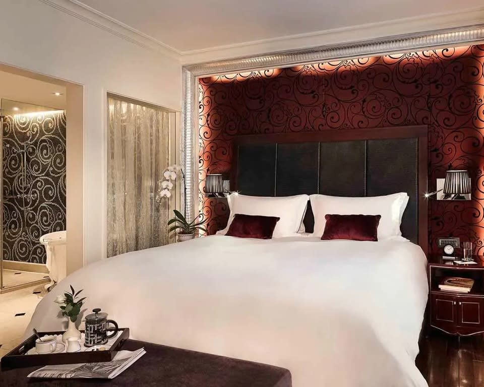 bedroom with white bed linens, brown headboard, and maroon walls