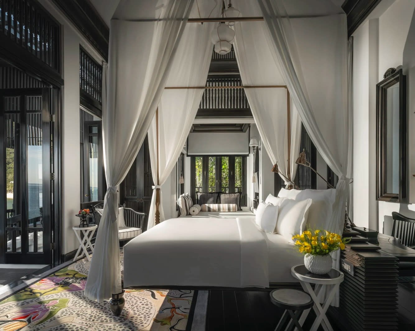 four poster bed with white linens and curtain, dark walls, and daylight