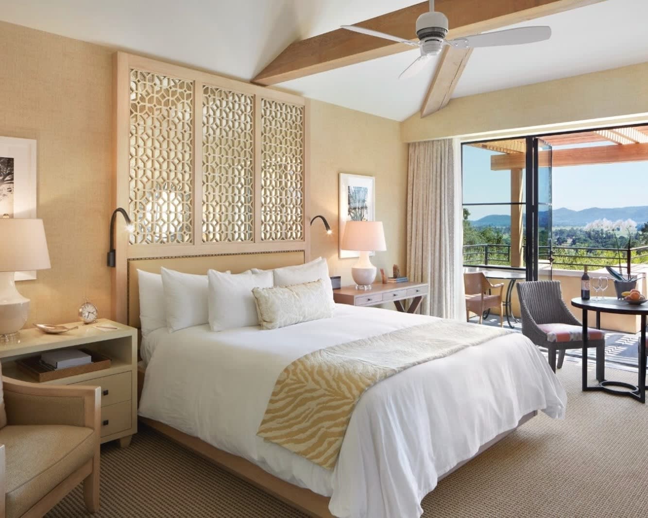 hotel room with white bed, neutral walls, and balcony with open doors and chair
