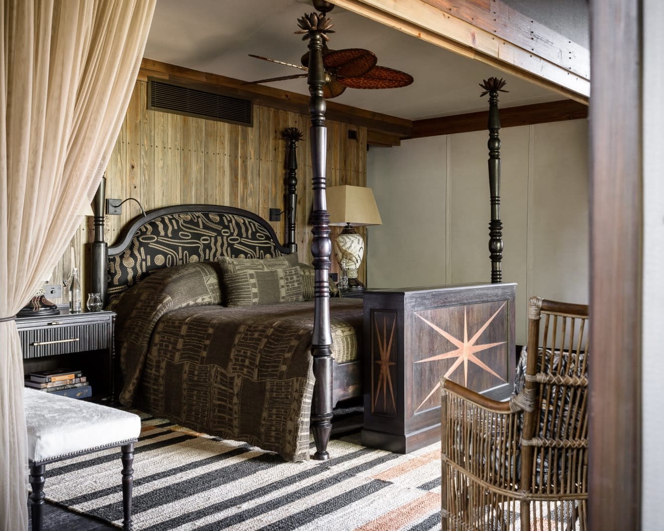 dark brown four poster bed frame, comforter, and furniture with white walls and tan curtains