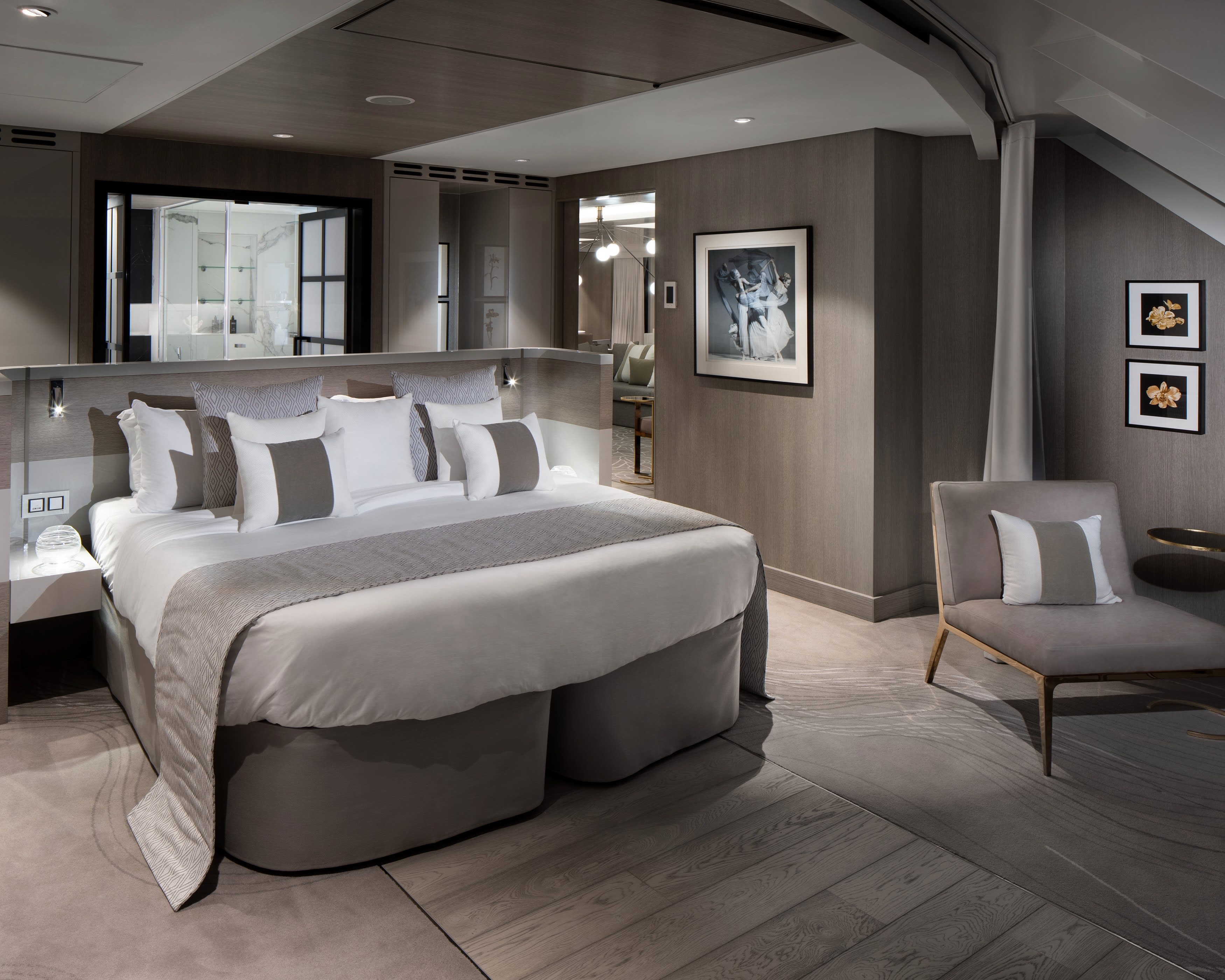 grey and white colored room with bed, side chair, and bathroom in the background