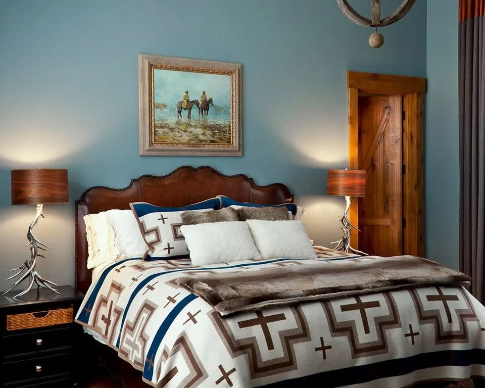 rustic white, brown and navy blue blanket on bed with tree branch lamps on bedside night tables
