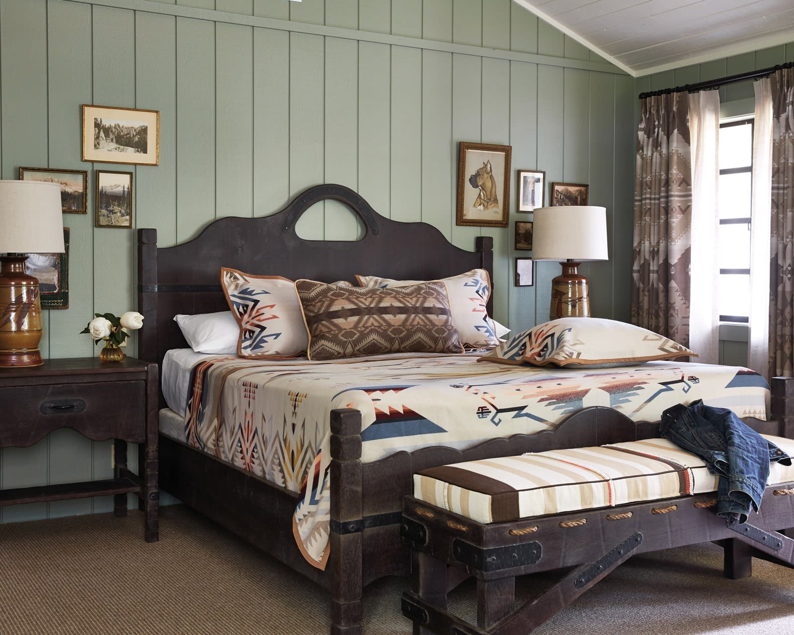 dark wood bed, ottoman and bedside nightstands with light green walls in rustic hotel room