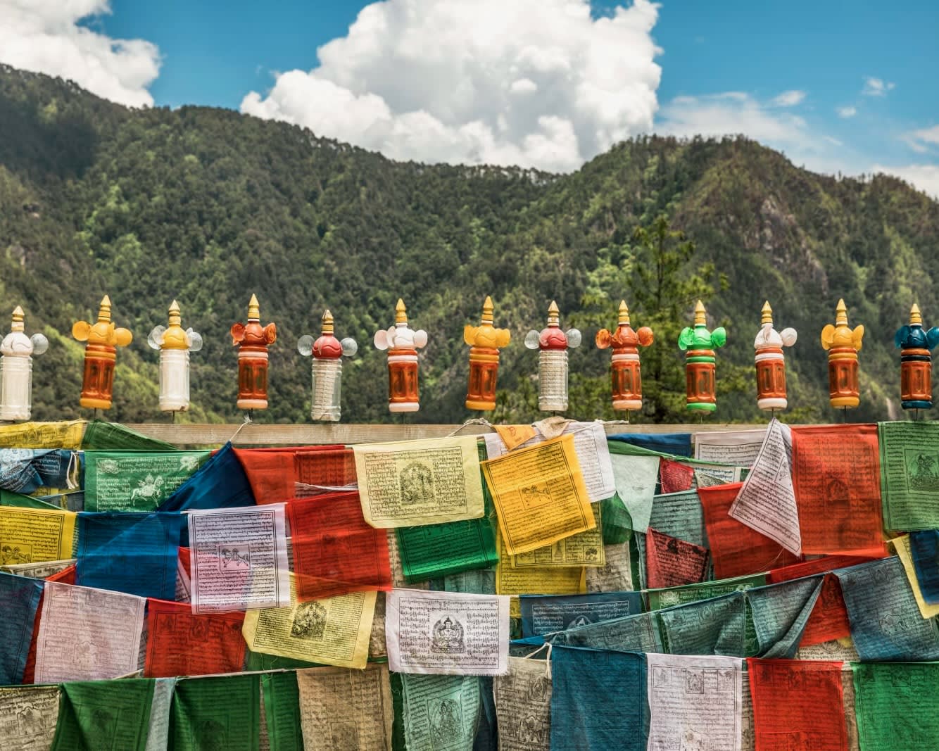 colorful prayer flags under a green mountain