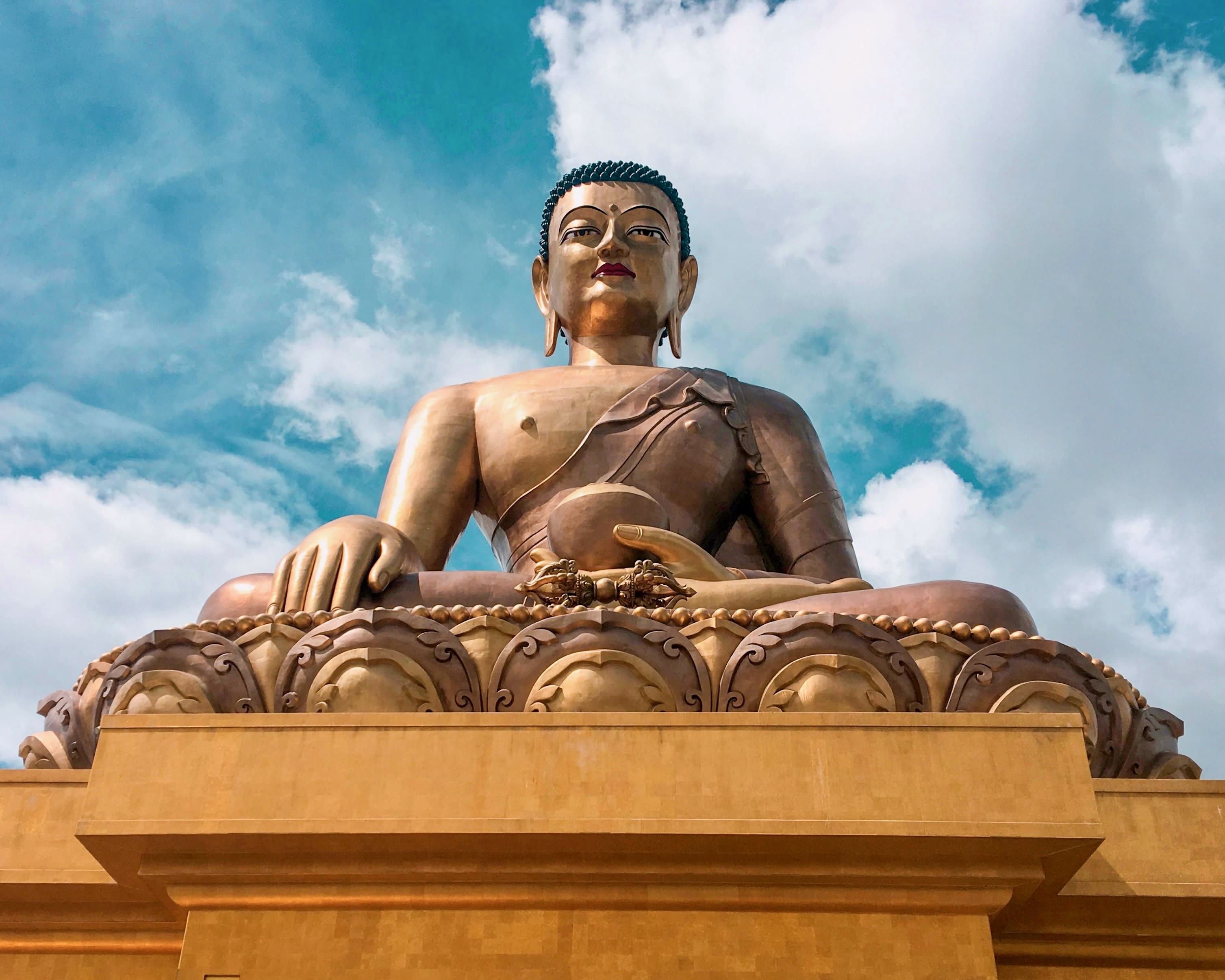 golden buddha statue under a partly cloudy blue sky during day