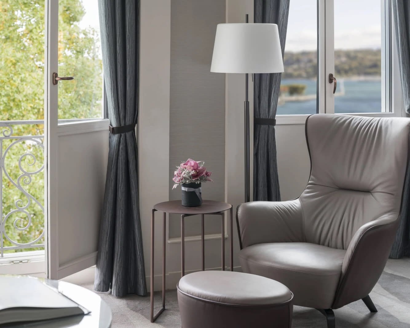 grey chair and ottoman next to a window and open balcony door