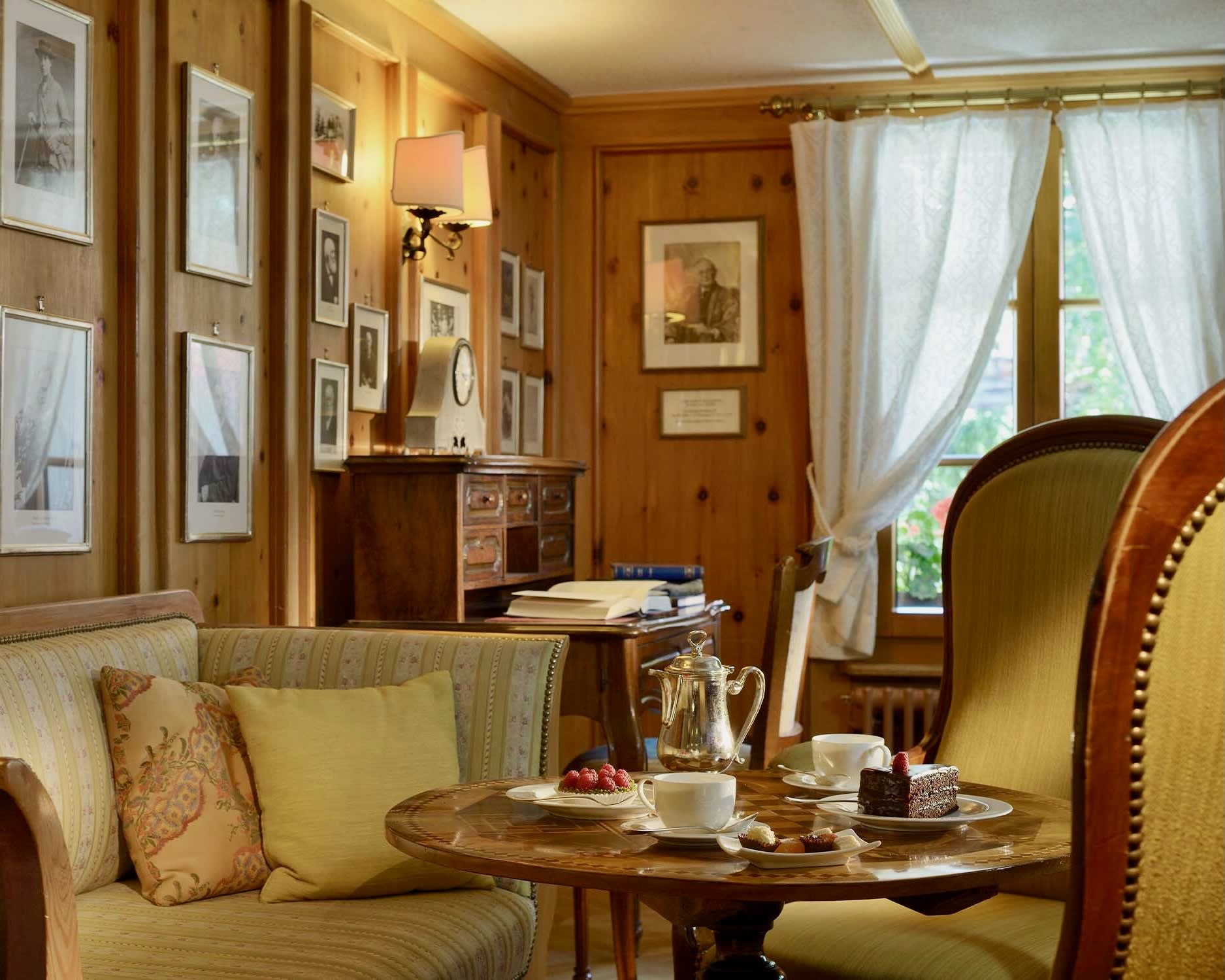 tea set on a table with chairs and loveseat next to framed photos on wood walls