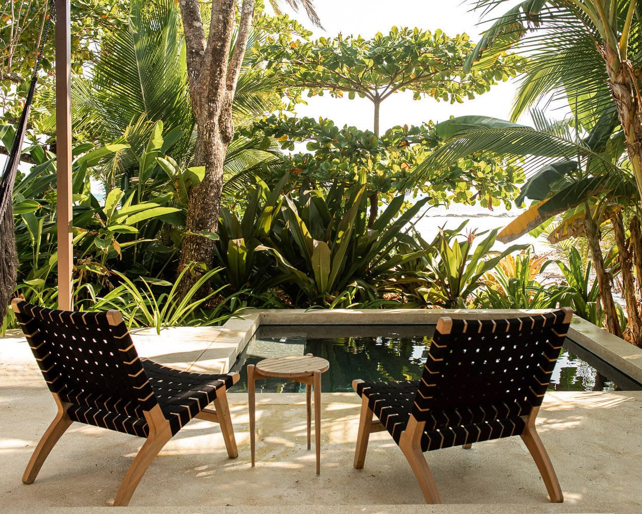 two low black chairs overlooking a plunge pool and green trees