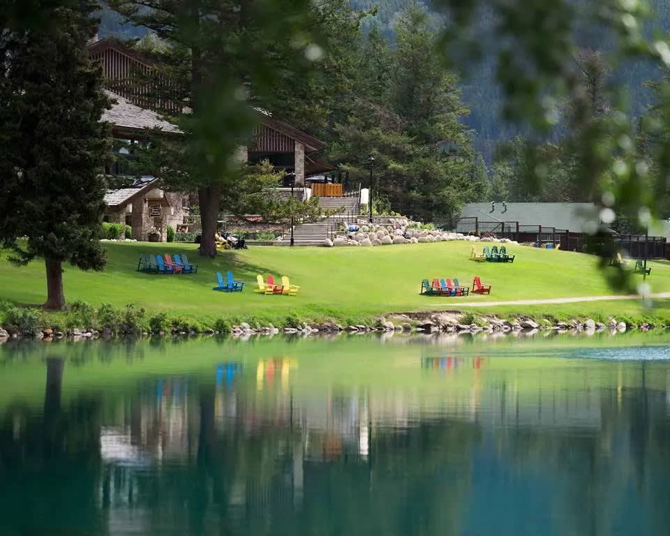 lakeside resort with Adirondack chairs facing the water under trees