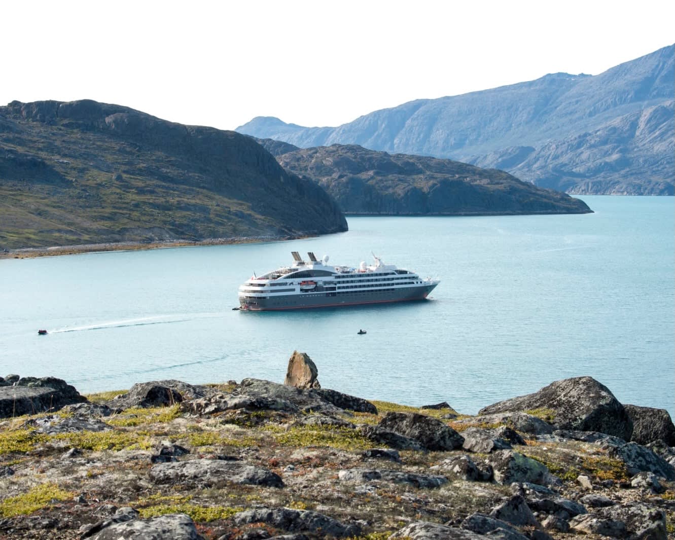 expedition cruise ship in a remote bay with rocky mountains on all sides