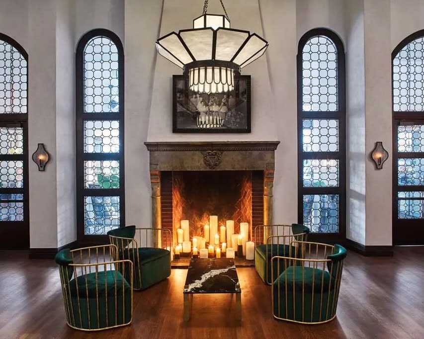 grand lobby fireplace with candles, fronted by two chairs under a chandelier