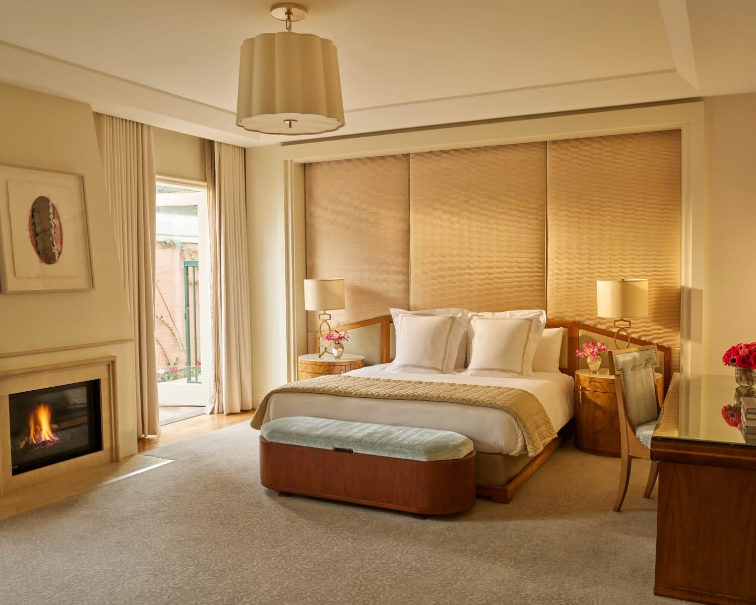 large white bed under a tan cushioned wall headboard and a fireplace off to the side