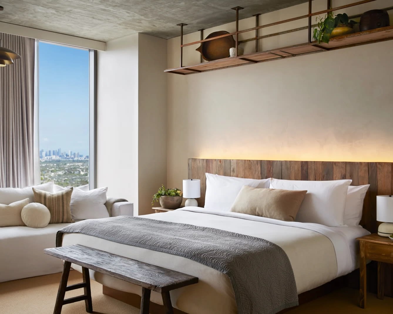 modern hotel room with white linen bed, grey accents, and a white sofa under a panoramic window