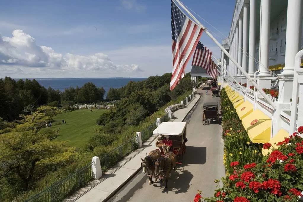 A horse carriage rides down the street in front of Grand Hotel Mackinac Island