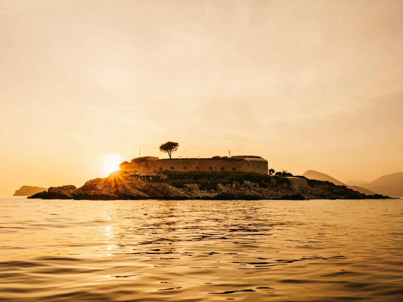 sun setting behind an island fortress