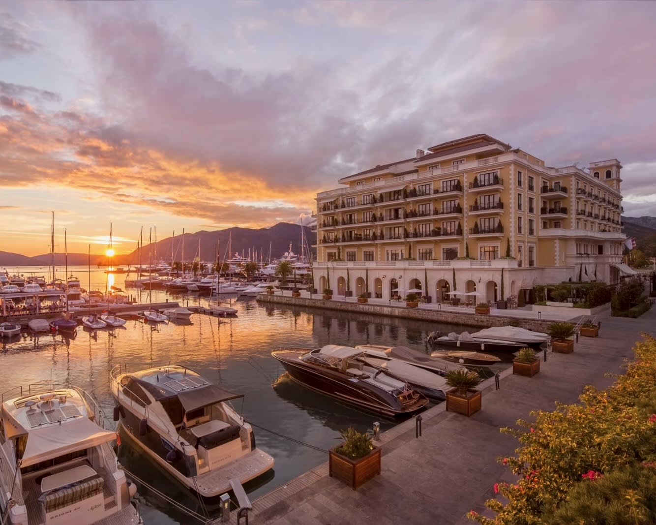 sun setting behind a yacht lined marina next to a luxury hotel