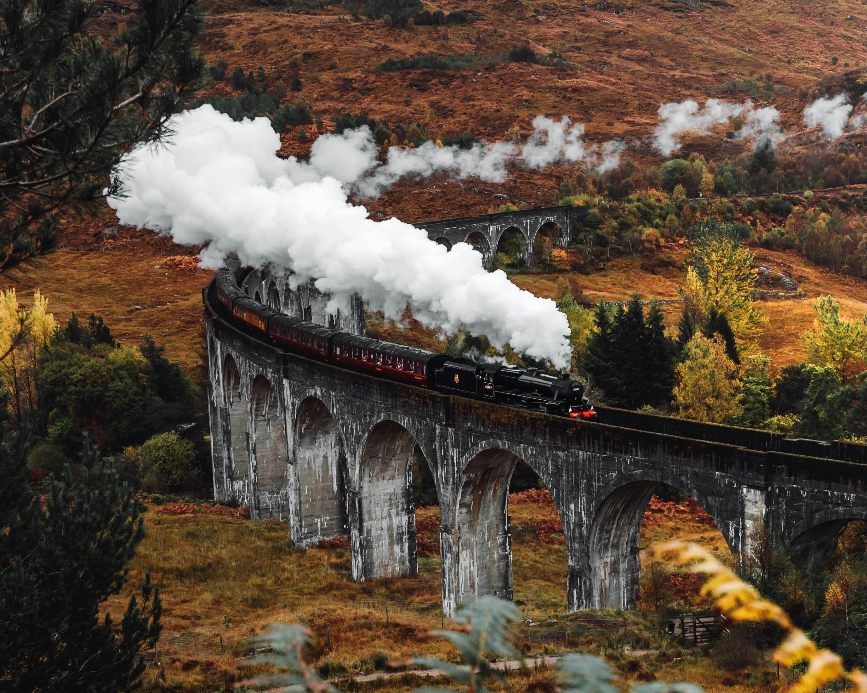 steam train on a curved viaduct train track through the country