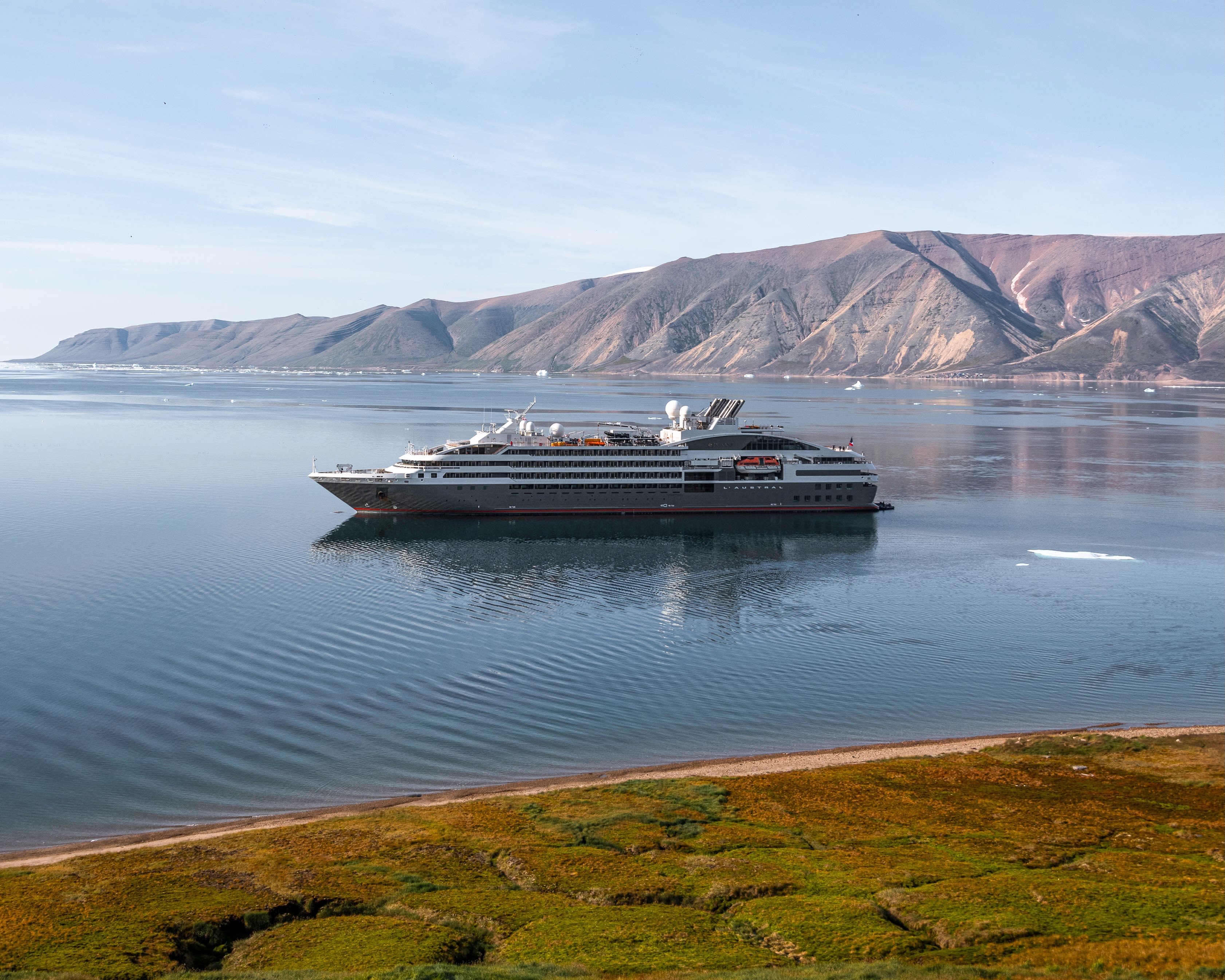 expedition ship offshore with mountains in the background
