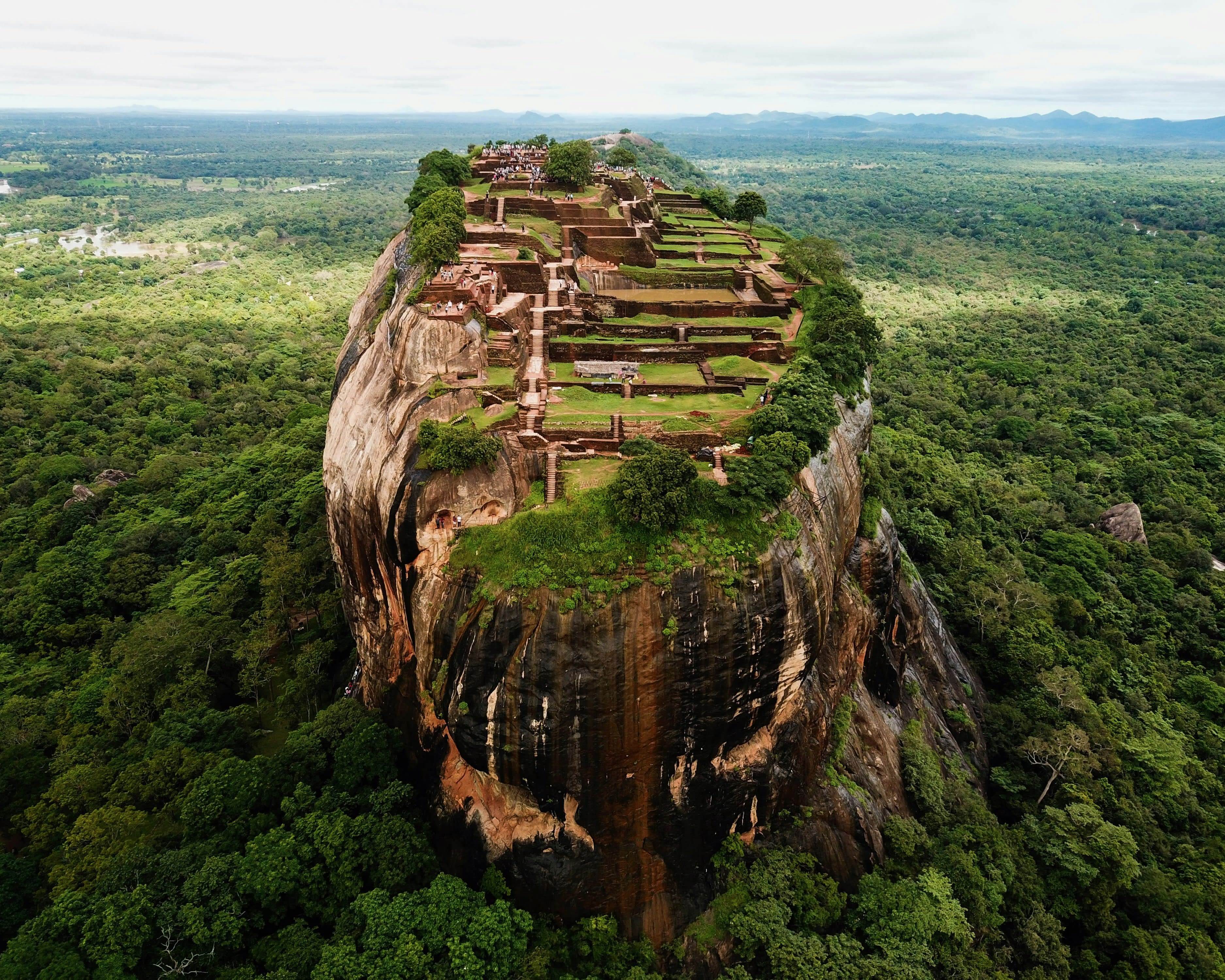 ancient rock fortress on top of a tall rocky mountain in the middle of a green jungle