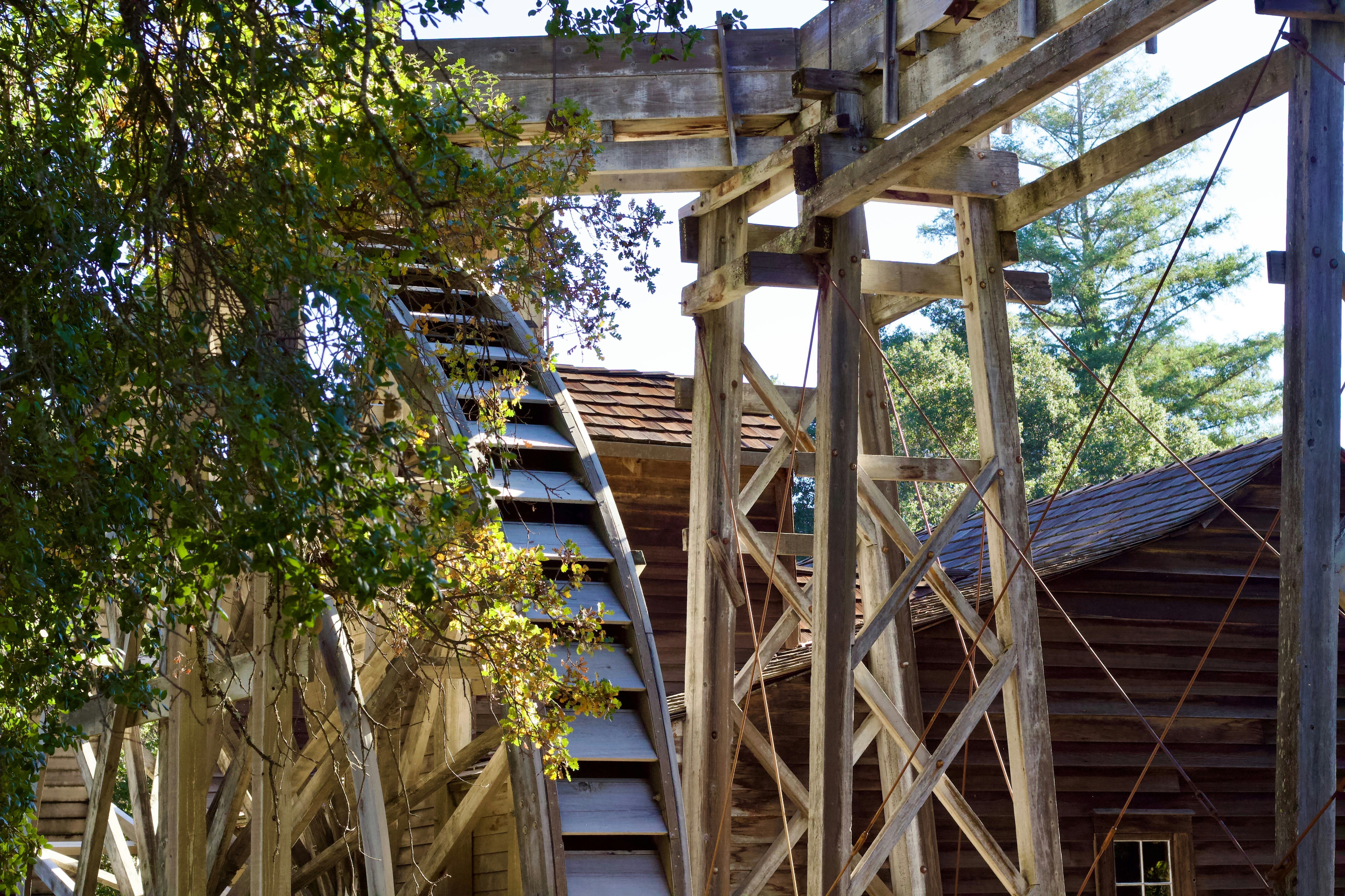 wood water mill behind trees during daytime